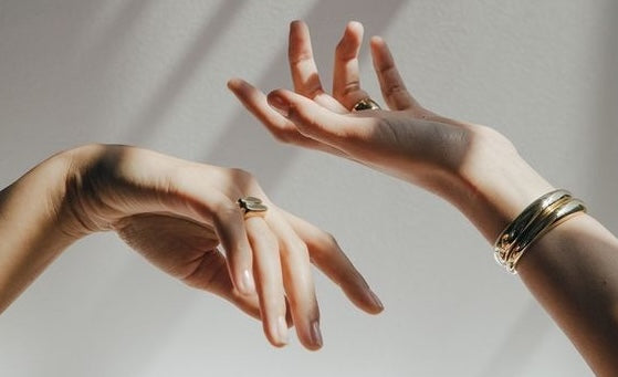 two hands wearing golden jewellery